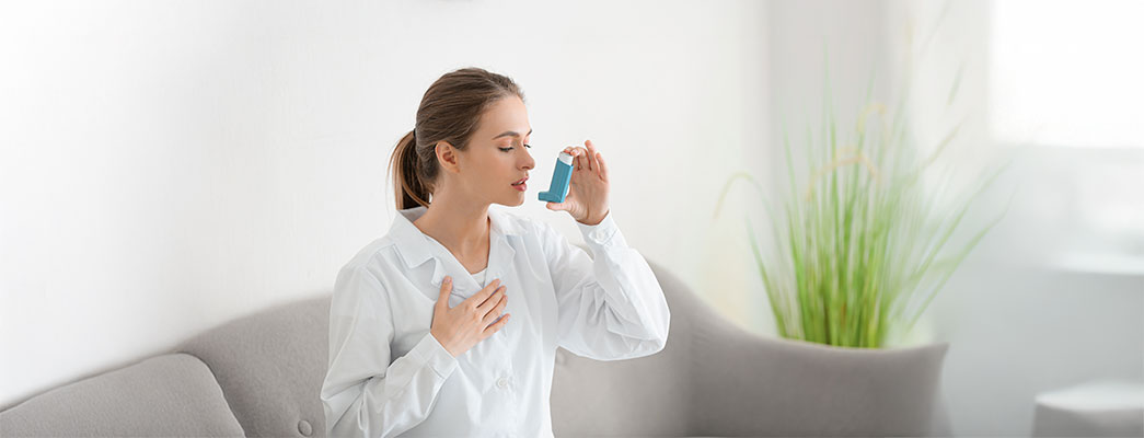 Junge Frau auf dem Sofa hält einen Inhalator in der Hand