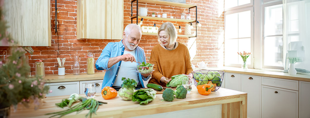 Älteres Ehepaar kocht zusammen mit frischen Zutaten