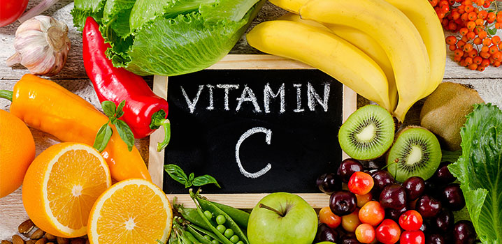 Schiefertafel mit dem Schriftzug Vitamin C, umgeben von Obst und Gemüse