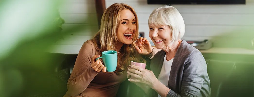 Zwei Frauen sitzen auf der Couch und reden miteinander.