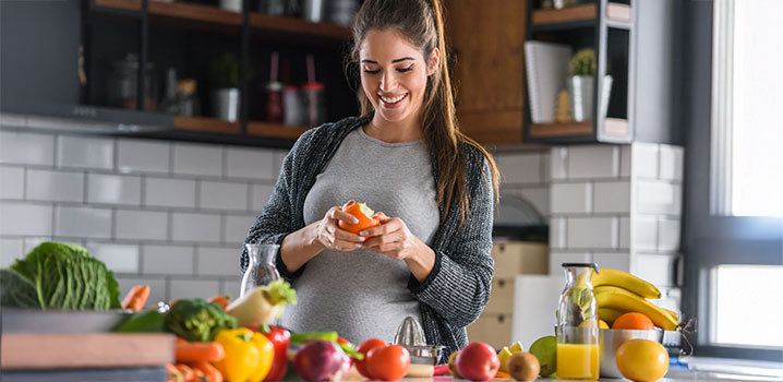 Junge Frau steht in der Küche und schält eine Mandarine