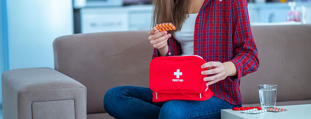 Frau auf Sofa mit Erste-Hilfe-Koffer