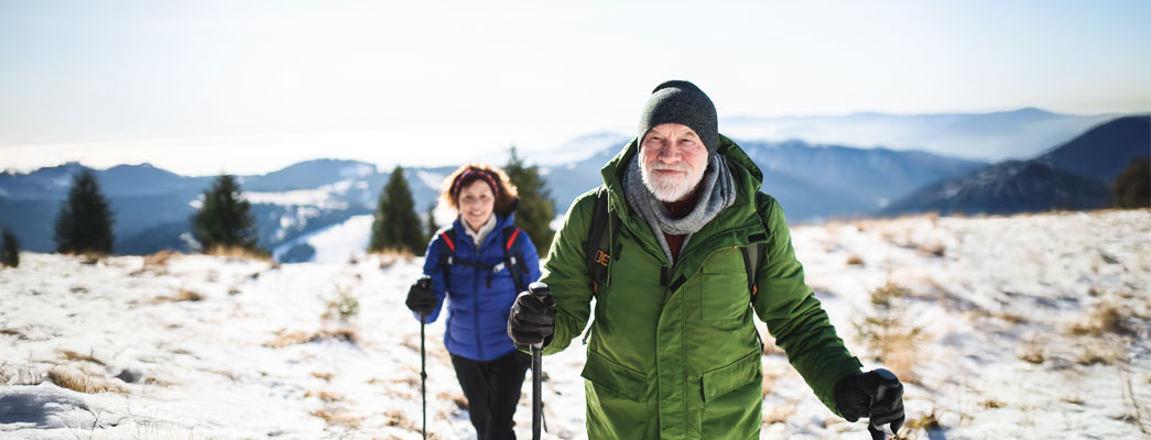 Älteres Ehepaar geht im Winter mit Walkingstöcken spazieren