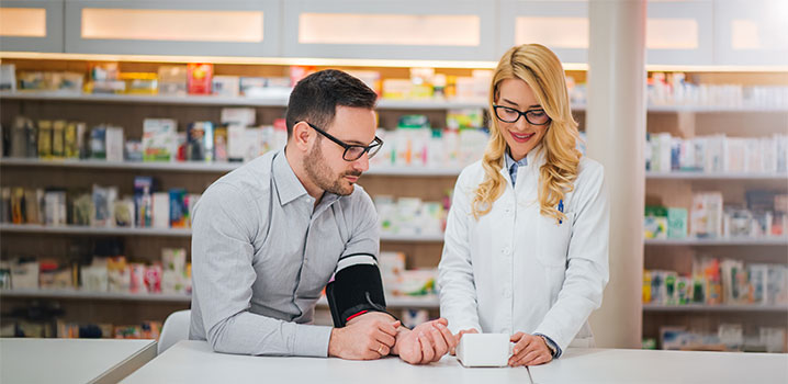 Junger Mann lässt sich von einer Apothekerin den Blutdruck messen