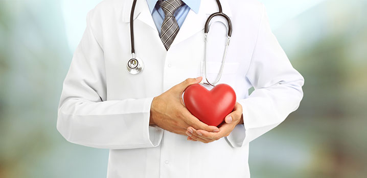 Person im Arztkittel die sich ein Herz vor die Brust hält