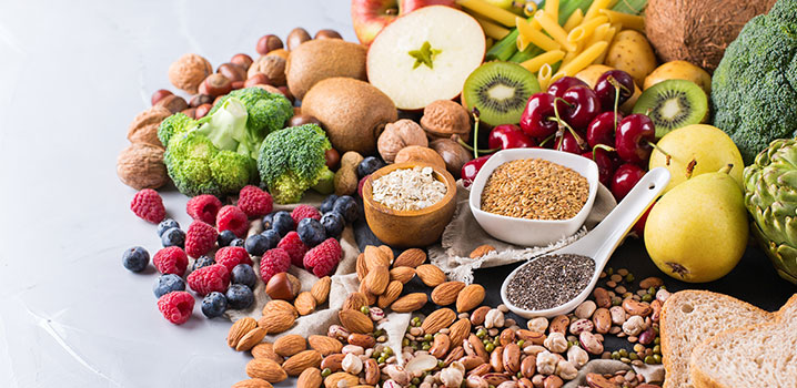 Verschiedene Lebensmittel wie Obst, Gemüse und Nüsse liegen auf einer Tischplatte