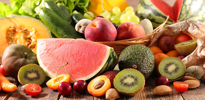 Holztisch, auf verschiedene Früchte wie Melone, Kiwi, Aprikose und Weintrauben liegen