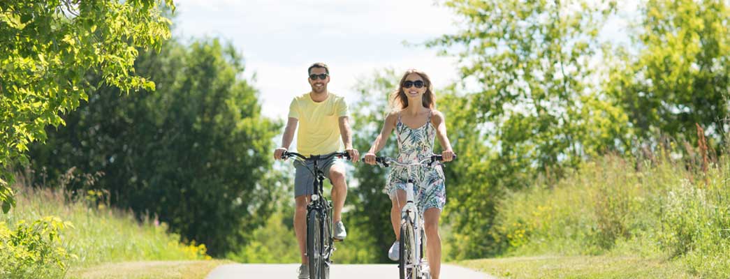 Mann und Frau fahren mit dem Fahrrad durch eine grüne Landschaft