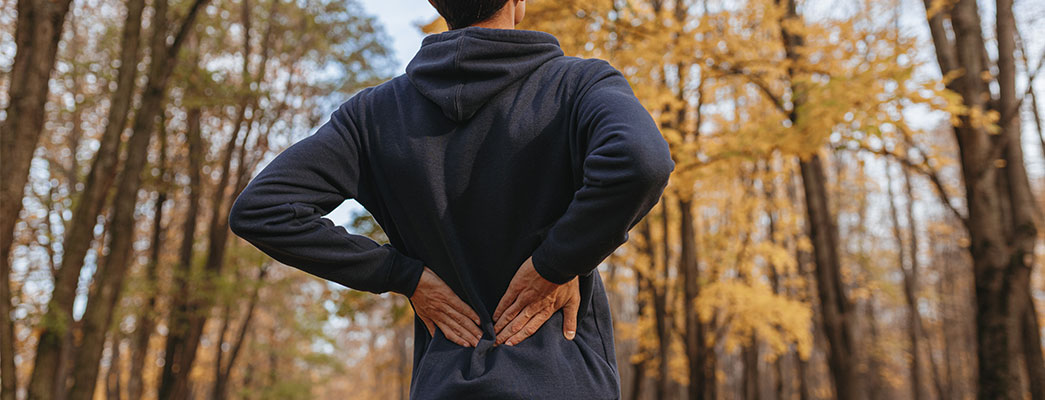 Mann von hinten der sich den Rücken hält