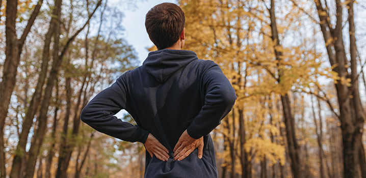 Mann von hinten der sich den Rücken hält