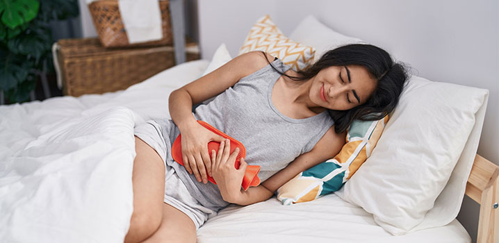 Frau mit Wärmflasche im Bett