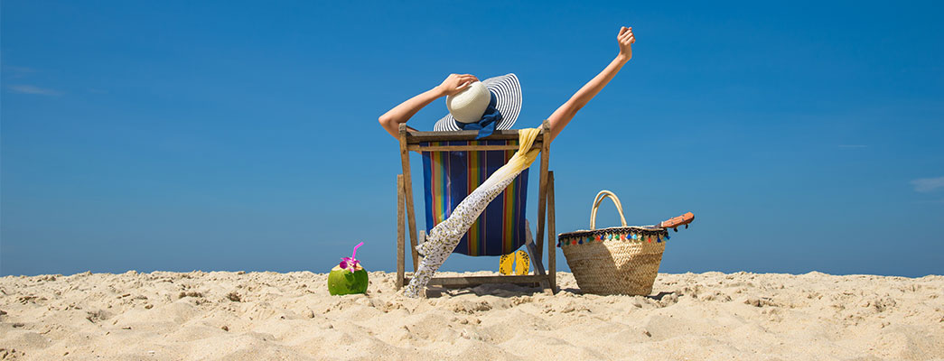 Frau sitzt im Liegestuhl am Strand