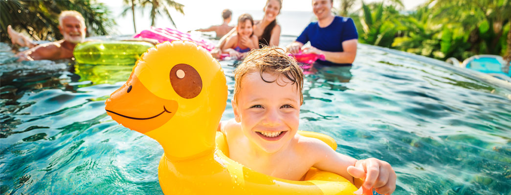 Junge badet mit aufblasbarer Ente im Swimmingpool