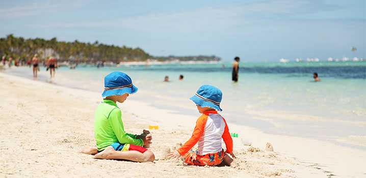 Zwei Kleinkinder sitzen am Strand und spielen